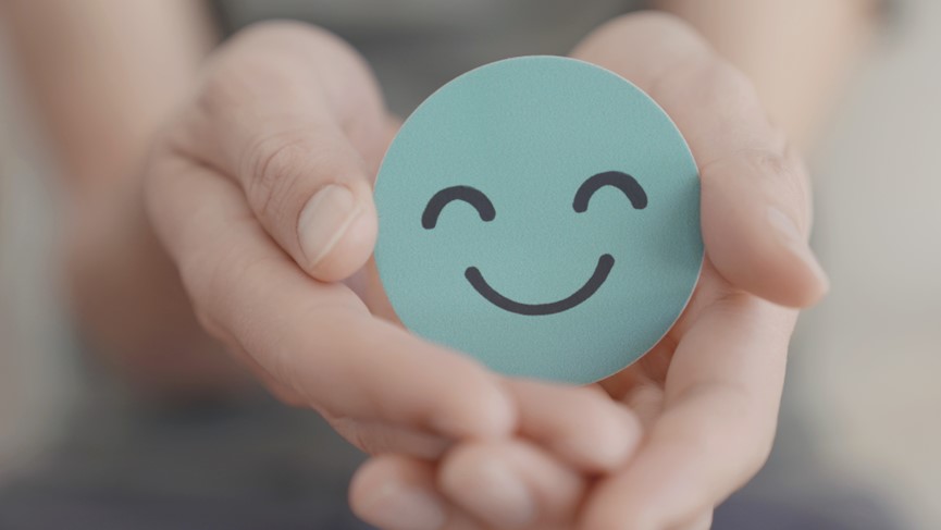 Über uns Dekoratives Bild Zwei Hände halten einen runden Smiley-Aufkleber, der lächelt.